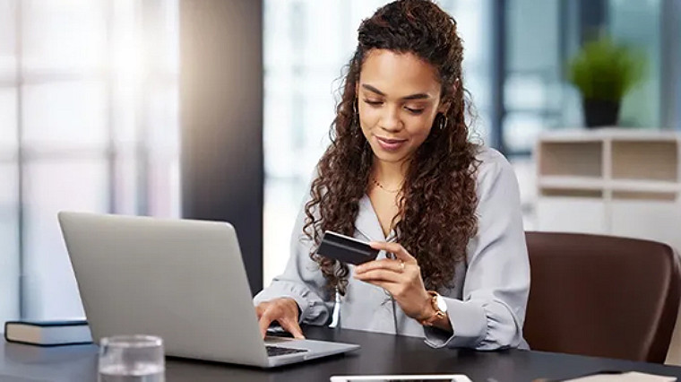 Person making an online payment using a laptop and card