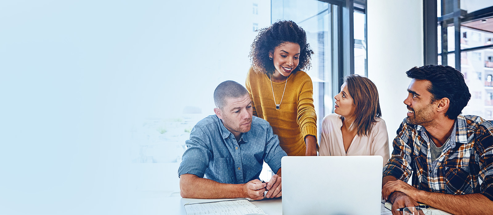 A group of diverse individuals collaborating on a laptop