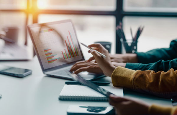 Business professionals collaborating on a laptop displaying various graphs and data analysis.