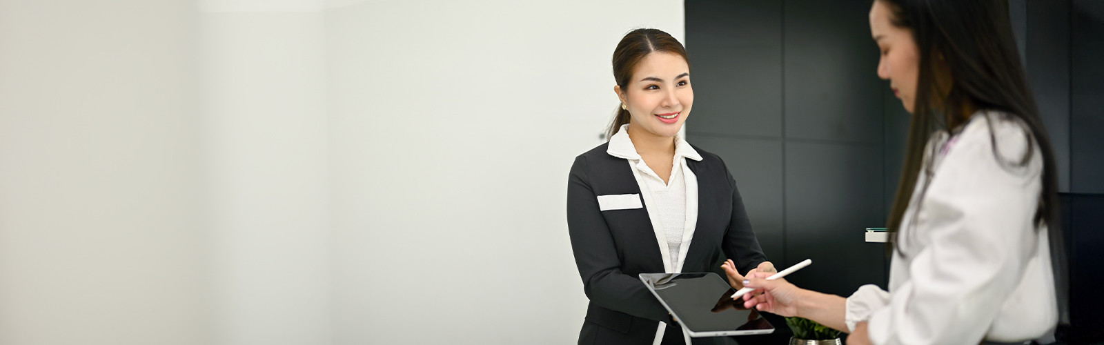 One woman holding a tablet while another woman writes on it with a digital pen