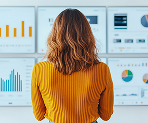 View of back of a woman looking at a wall of graphs.