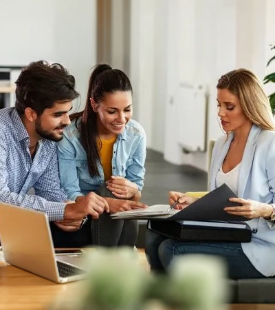 A lady sitting with an open document and explaining something to a couple