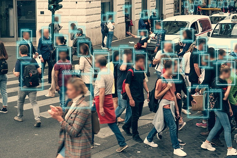 Personnes traversant une route, le visage de chaque personne étant scanné par des caméras de reconnaissance faciale.