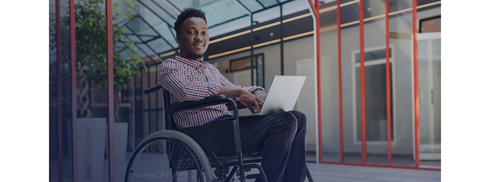 A man sitting in a wheelchair having laptop on his laps.