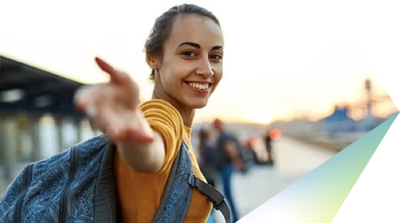 Mujer con una blusa amarilla, sonriendo y extendiendo su mano derecha hacia la cámara