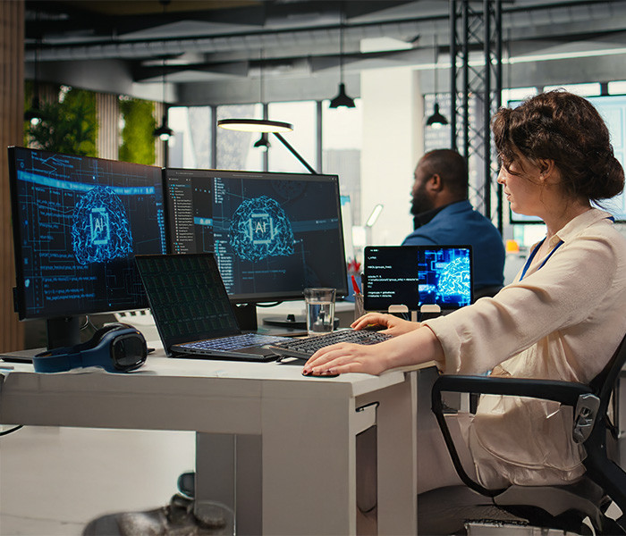 A woman operating two computers in a research lab