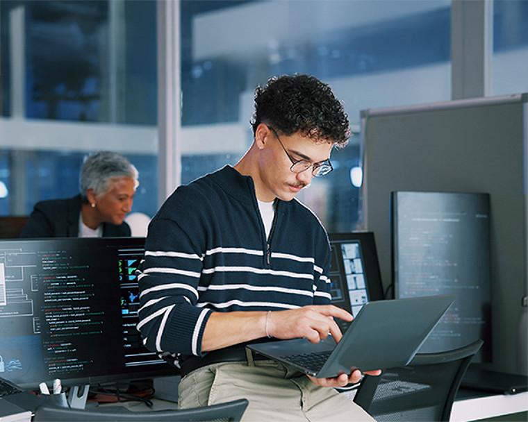 A person working on a laptop in an office environment.