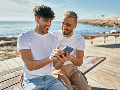 Individuals using mobile device on a beach. 