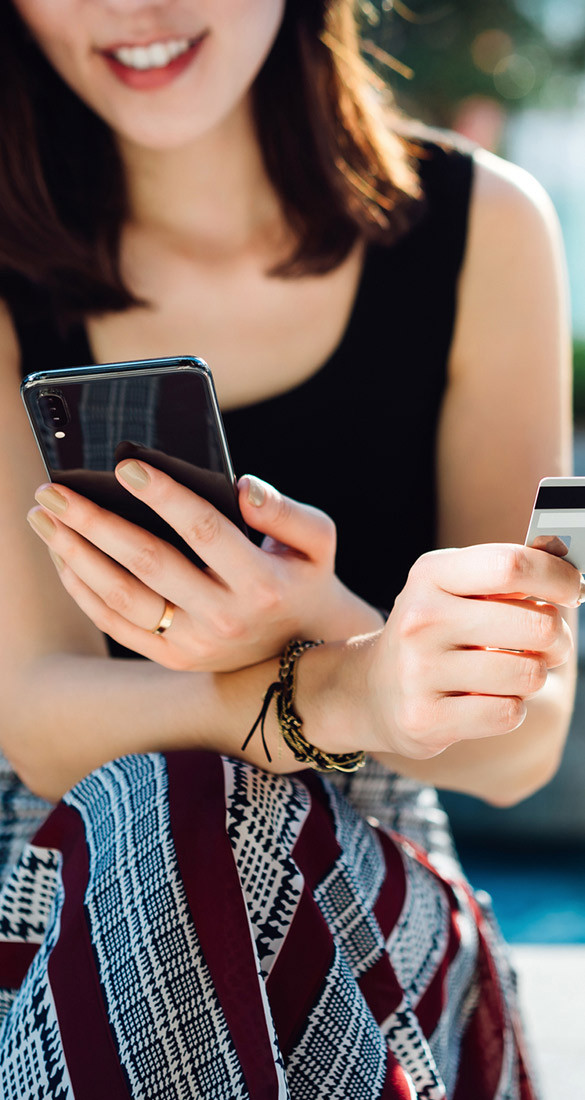 A set of hands holding cellphone in one and credit card in the other