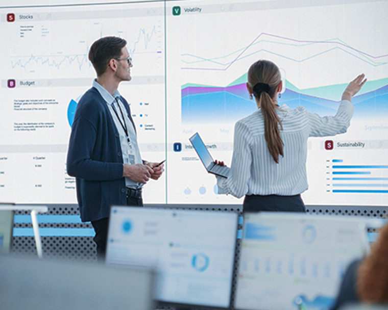 Two professionals analyzing graph in bigger screen