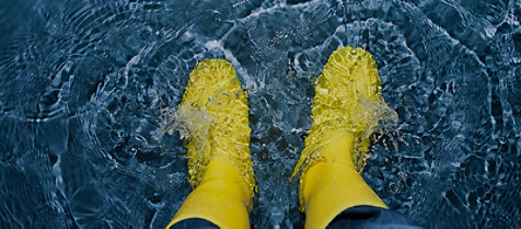 Gelbe Stiefel, die Wellen im Wasser machen