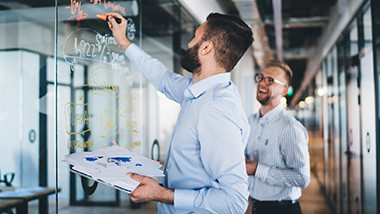 associates writing formulas on a large glass window