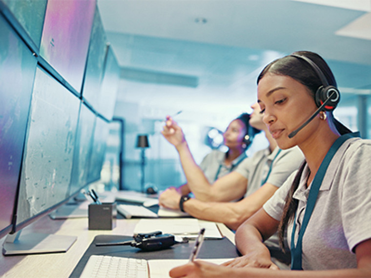 Empleados con auriculares sentados en fila frente a sus ordenadores