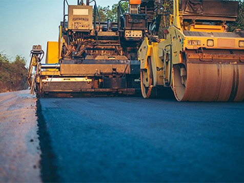 Una apisonadora compactando asfalto mientras construye una carretera