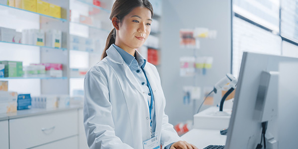 Eine Apothekerin, die im Stehen am Computer arbeitet