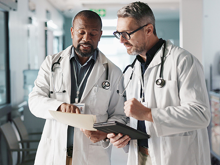 Healthcare professional reviewing tablet information with seated patient.