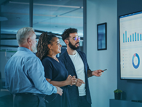 Three colleagues having a conversation and looking at presentation graph.