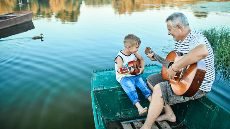 grandchild and grandfather playing guitar together