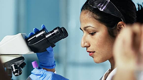 Kvinne ser under et miskroskop.