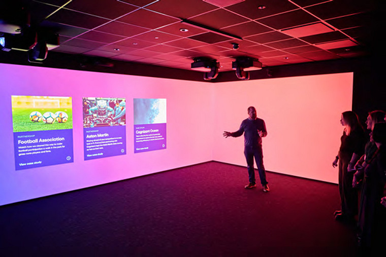 Several individuals gather in front of a large screen