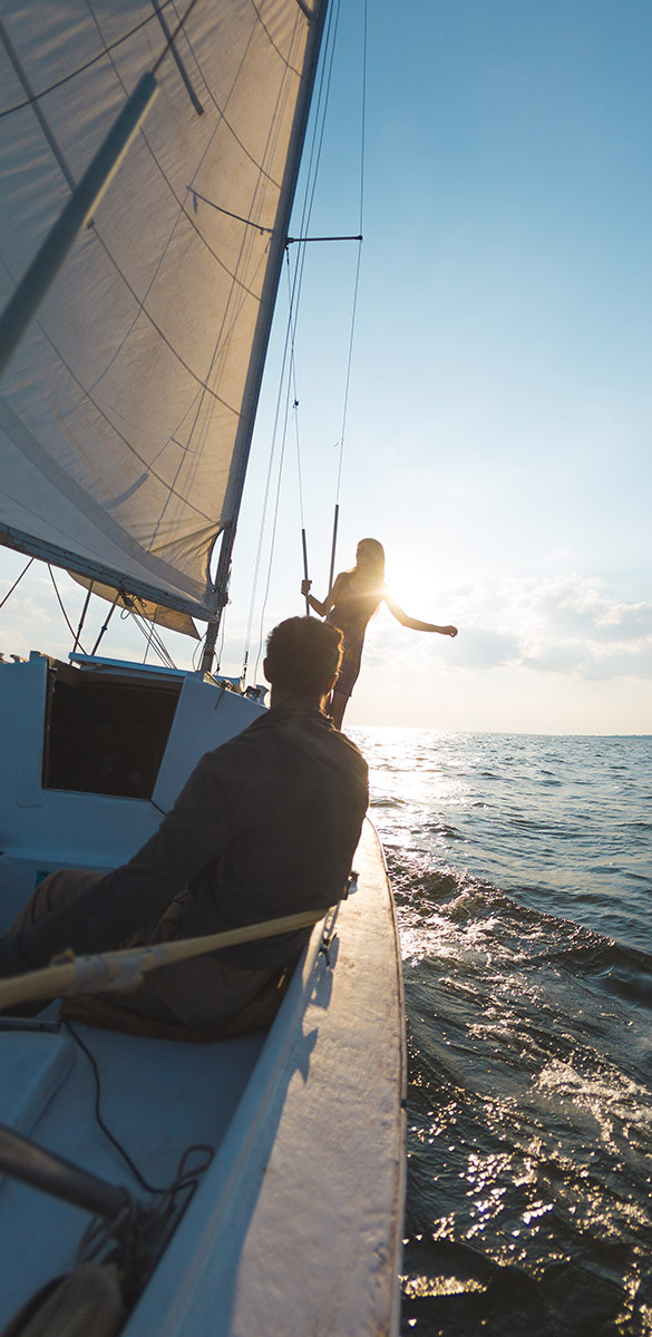 Man looking at woman on sailboat with sun in background