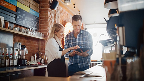 barista and cafe owner discuss work schedule and menu on tablet computer