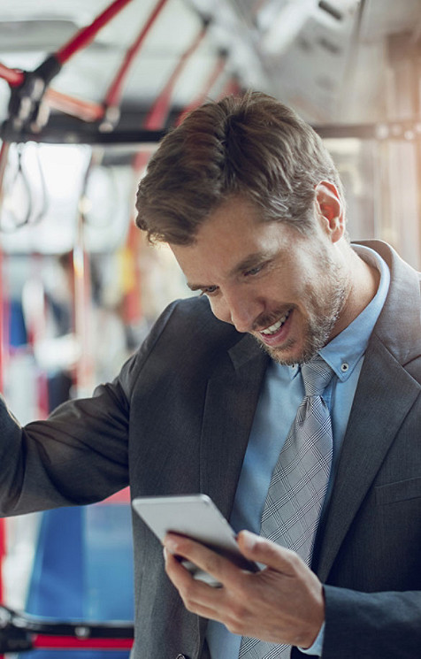 A man in a suit browsing his phone in a bus.