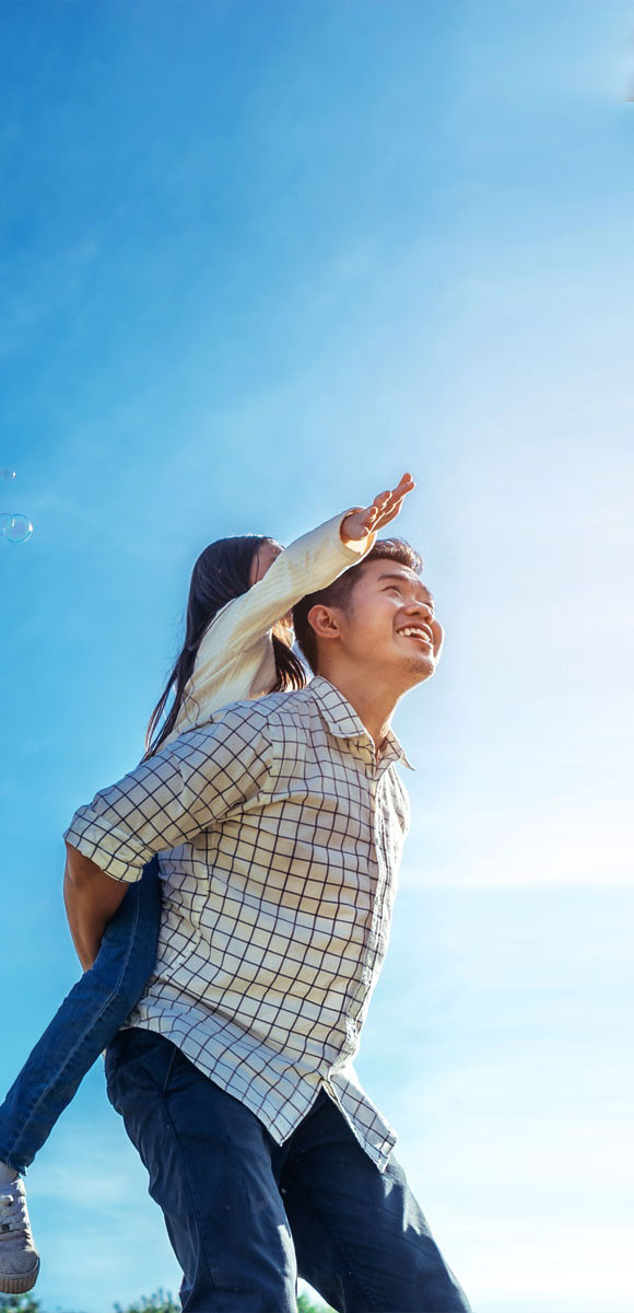 Man smiling and holding young girl on his back