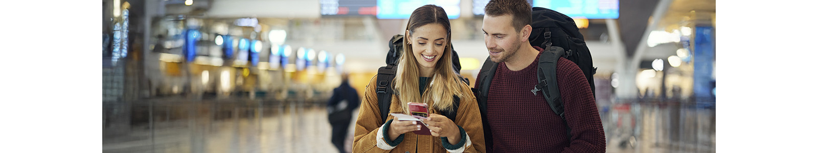 A couple travelling through an airport and checking a smartphone