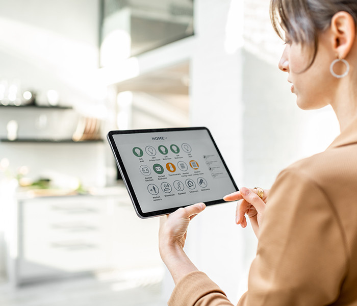 A lady holding a tablet and interacting with a smart home application