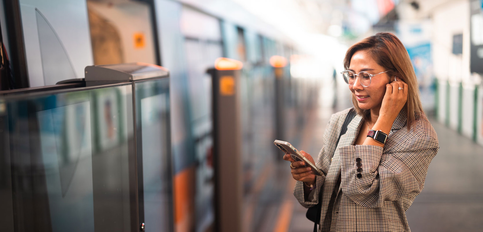 A woman wearing headphones stands in a bustling city
