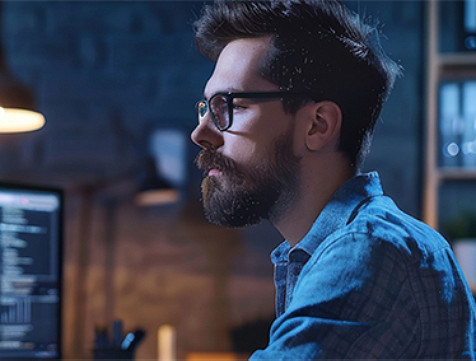 A side view of man face looking at computer monitor