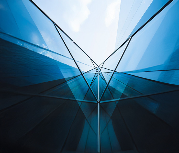 A low-angle view of a building with glass walls and the sky above it