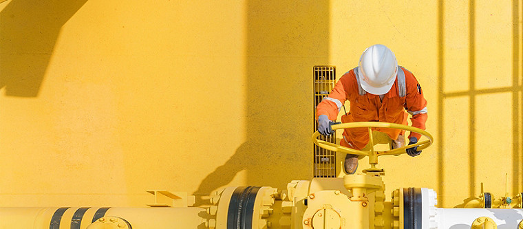 Ein Arbeiter in Warnschutzkleidung und weißem Helm bedient ein Ablassventil