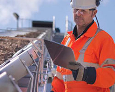 Homme sur un chantier portant un casque et regardant une tablette 