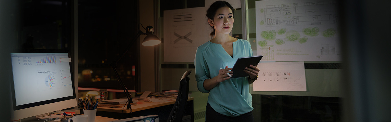 a woman standing with a tab in an office room.