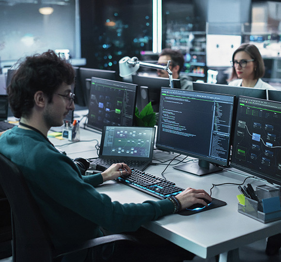 A group of diverse individuals seated around a table, each using a laptop for collaborative work.