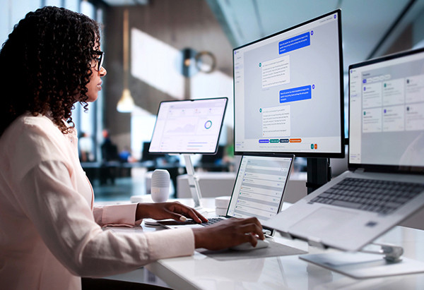 Professional using AI-powered workflow tools across multiple screens in a modern office environment