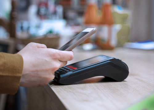 A mobile phone scanning over a handheld POS device.