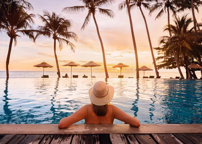 A woman in bikini relaxing at a holiday beach resort half submerged