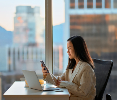 femme travaillant à un bureau et tenant un téléphone portable