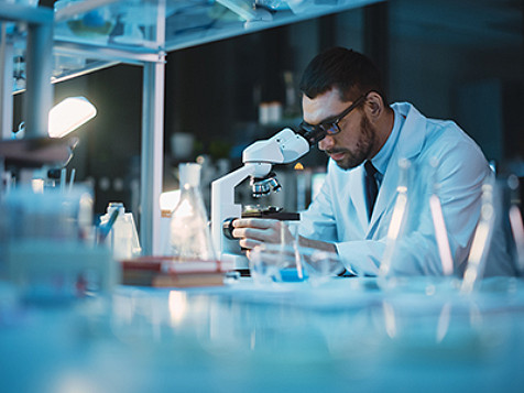 Un técnico de laboratorio mirando a través de un microscopio