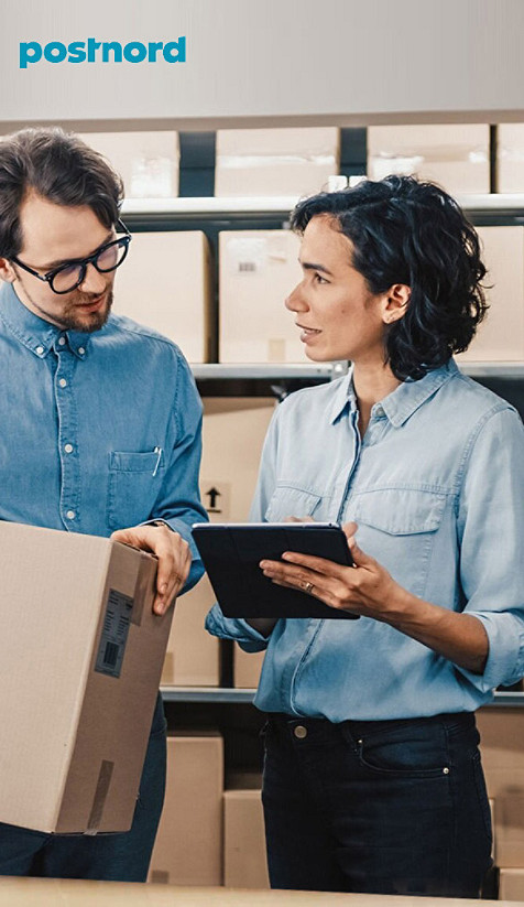 A man holding a package talking to a woman holding a tablet