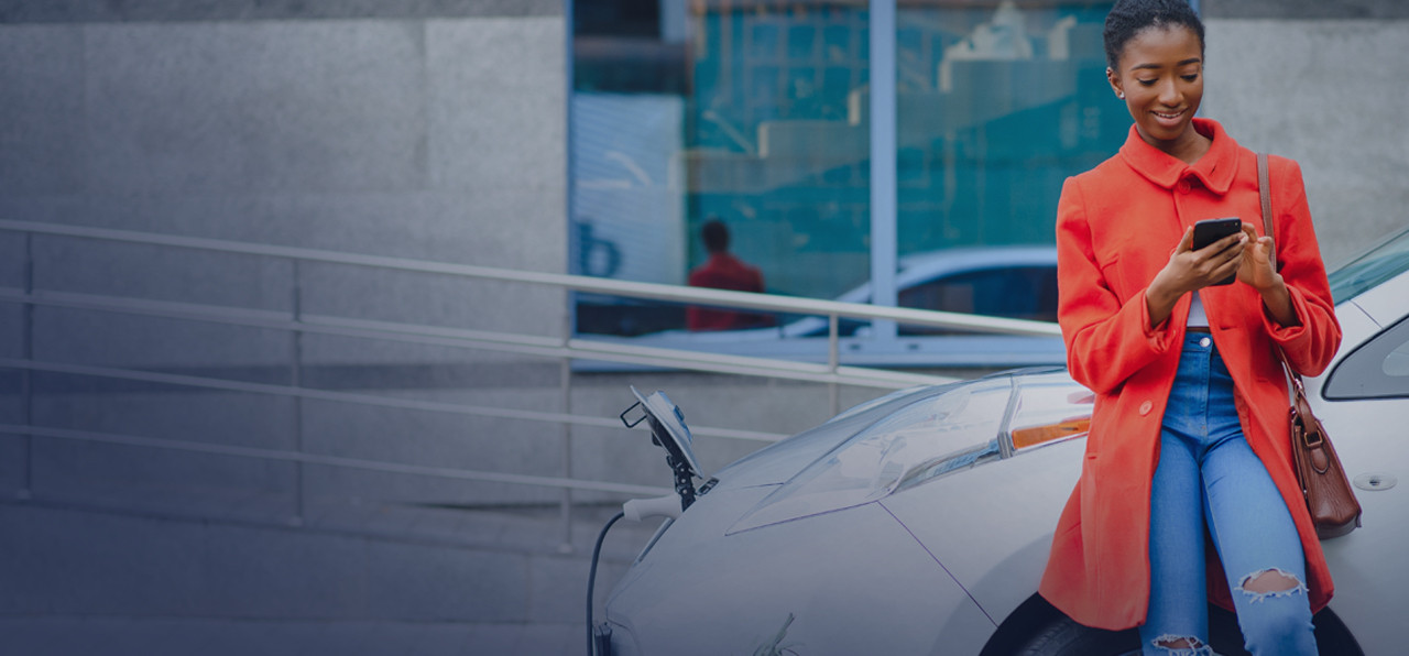 woman on her phone, waiting for her car's fule tank to be filled