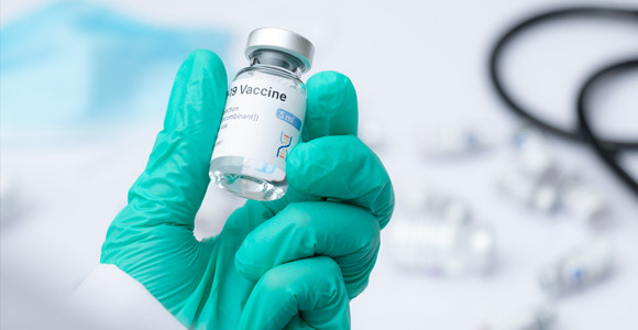 Mano con guante sosteniendo un vial de vacuna médica