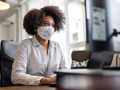 woman wearing mask working on computer