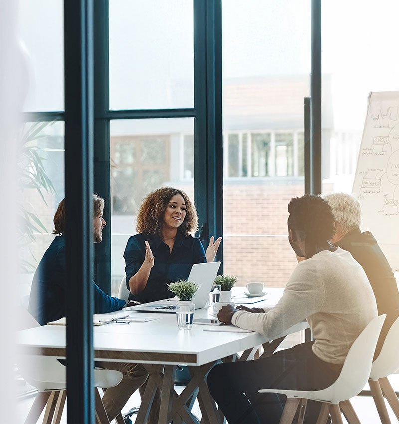 Four people are sitting at a meeting table, engaged in a discussion.