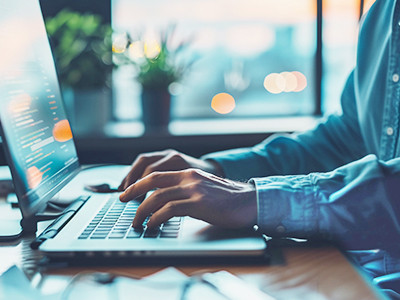 A pair of hands poised on a laptop