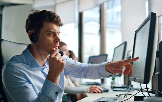 A man working at his desk pointing at the screen of his desktop