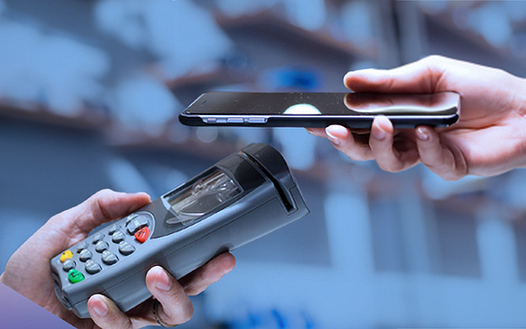 Close-up of two hands, one holding a card machine and the other a smartphone